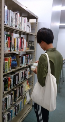 図書館で書籍を探す池上くん