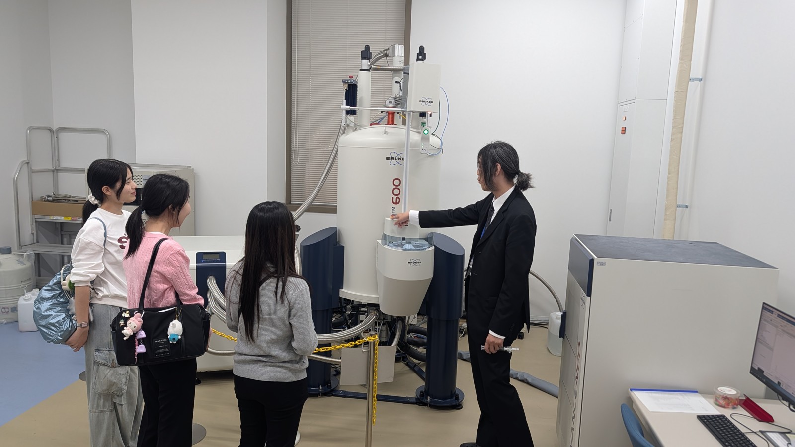 研究機器の前で説明を聞く訪問者の様子